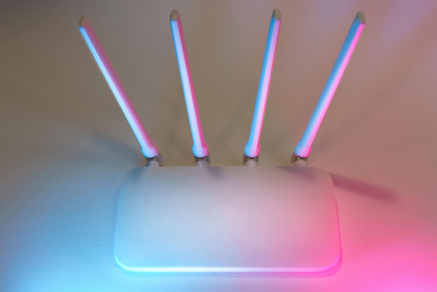 Router inalámbrico moderno con antenas y luces LED azules y rosas que representan la tecnología WiFi 7 Router inalámbrico moderno con antenas y luces LED azules y rosas que representan la tecnología WiFi 7