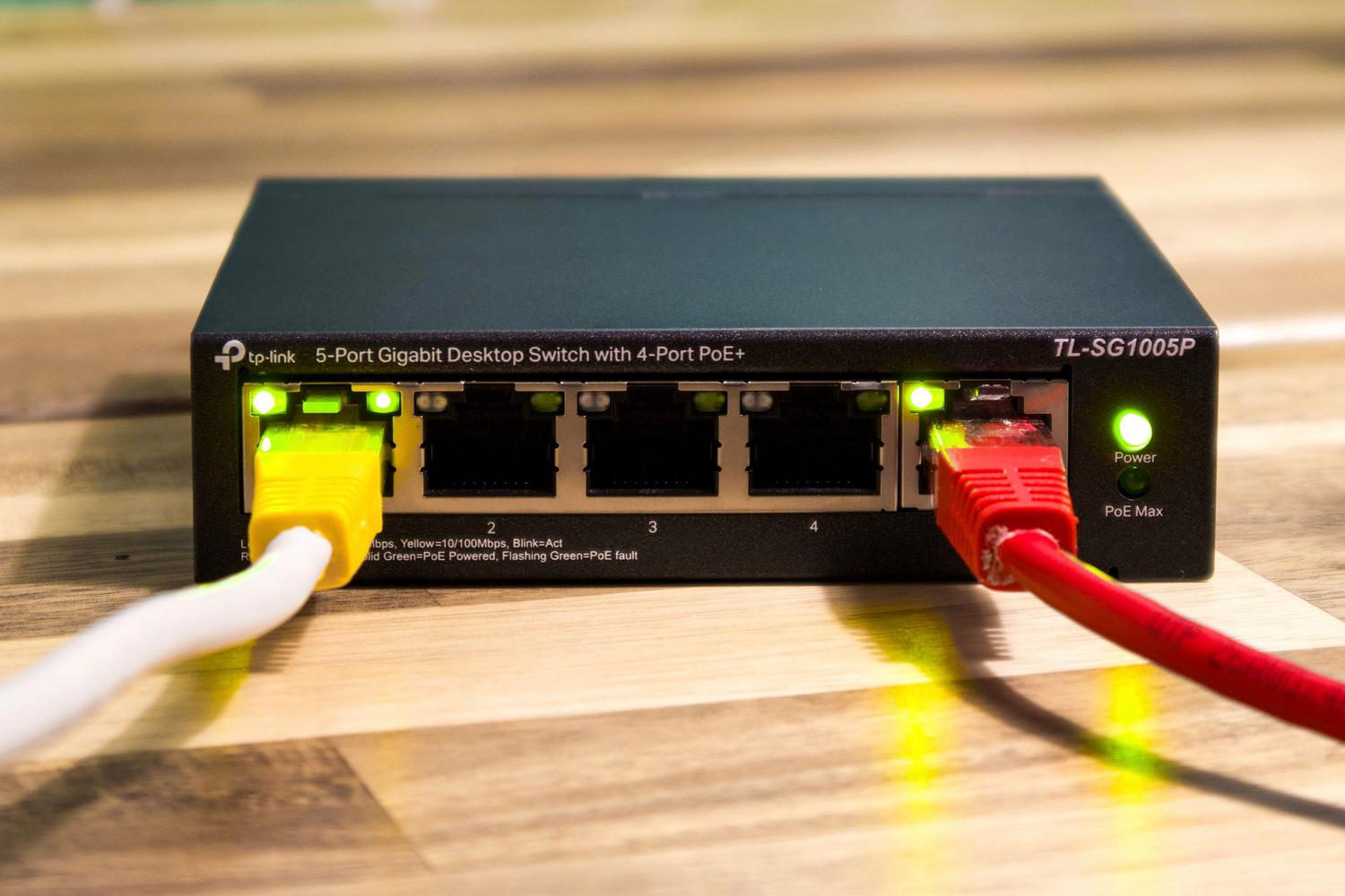 Switch de red Ethernet con cables conectados, representando la infraestructura de cableado necesaria para evitar cuellos de botella en redes WiFi 7 Switch de red Ethernet con cables conectados, representando la infraestructura de cableado necesaria para evitar cuellos de botella en redes WiFi 7