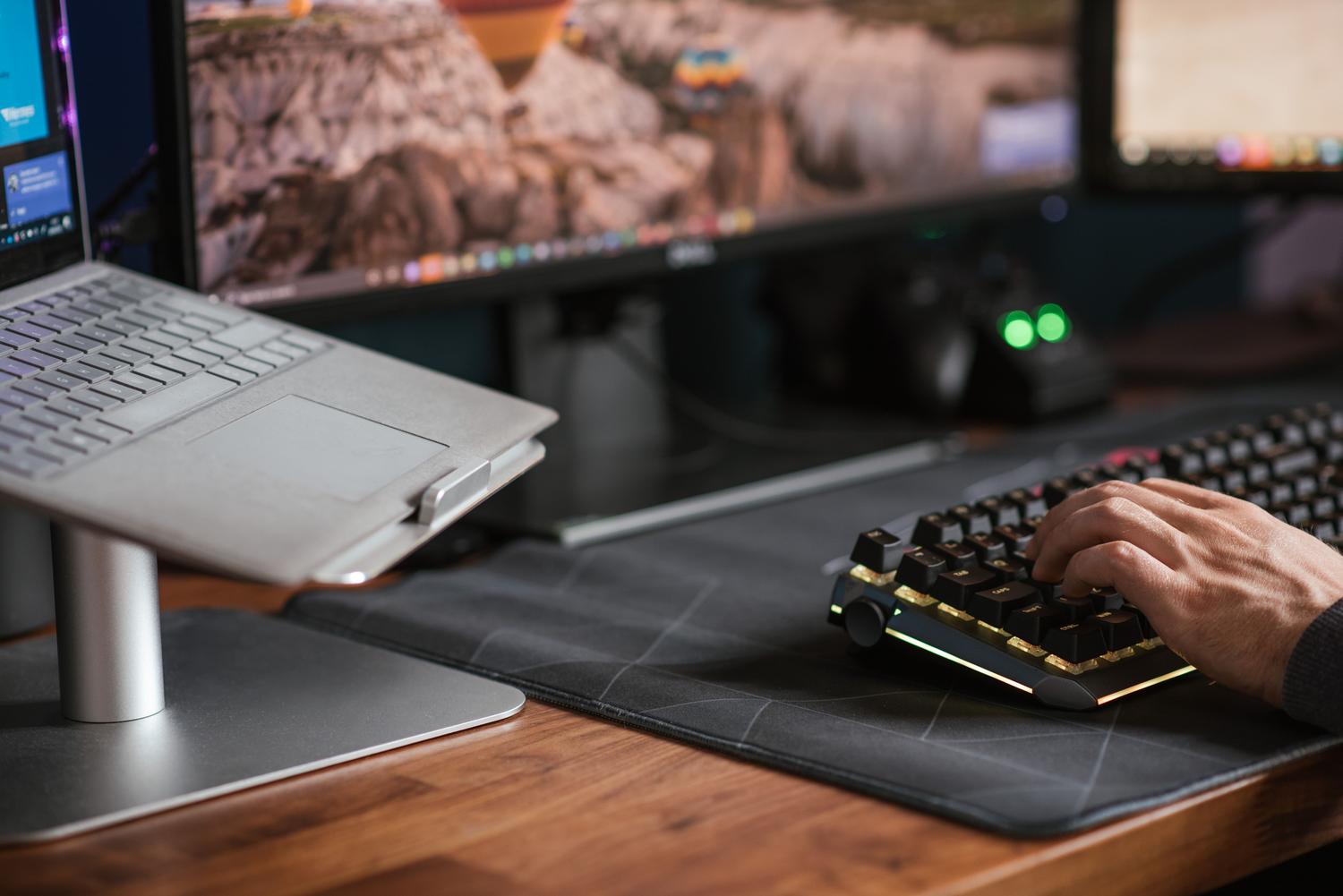 Detalle de un teclado mecánico y un ordenador portátil en un escritorio moderno Detalle de un teclado mecánico y un ordenador portátil en un escritorio moderno