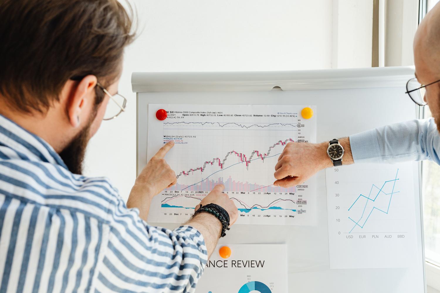 Colaboradores analizando tendencias de datos en una pizarra blanca en una oficina moderna. Colaboradores analizando tendencias de datos en una pizarra blanca en una oficina moderna.
