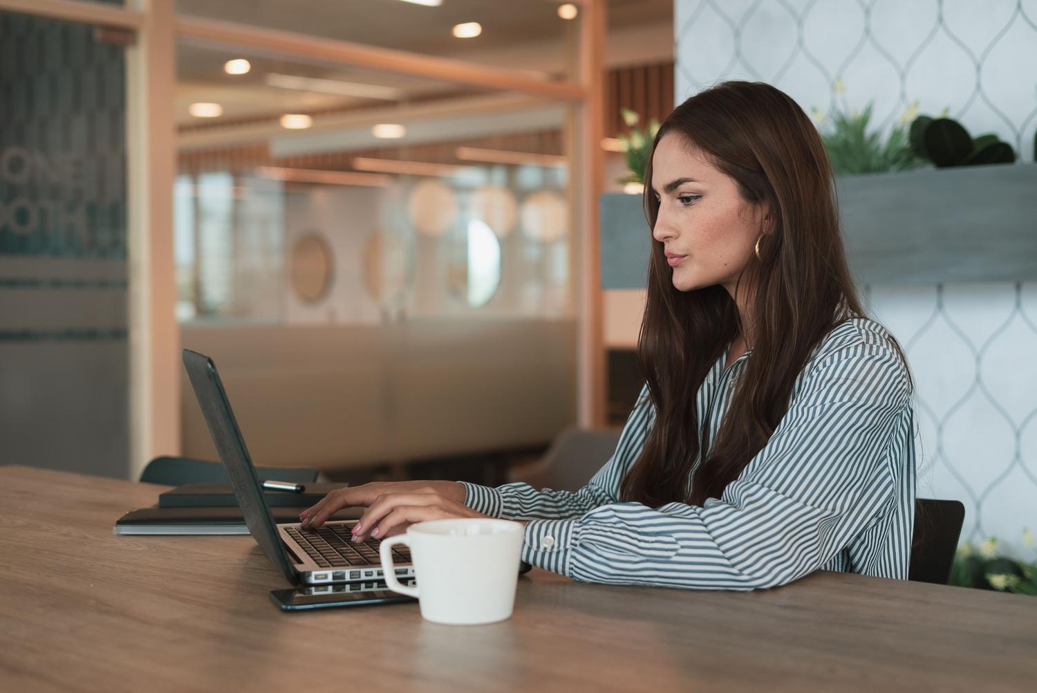 Mujer profesional trabajando con un portátil en una oficina moderna Mujer profesional trabajando con un portátil en una oficina moderna
