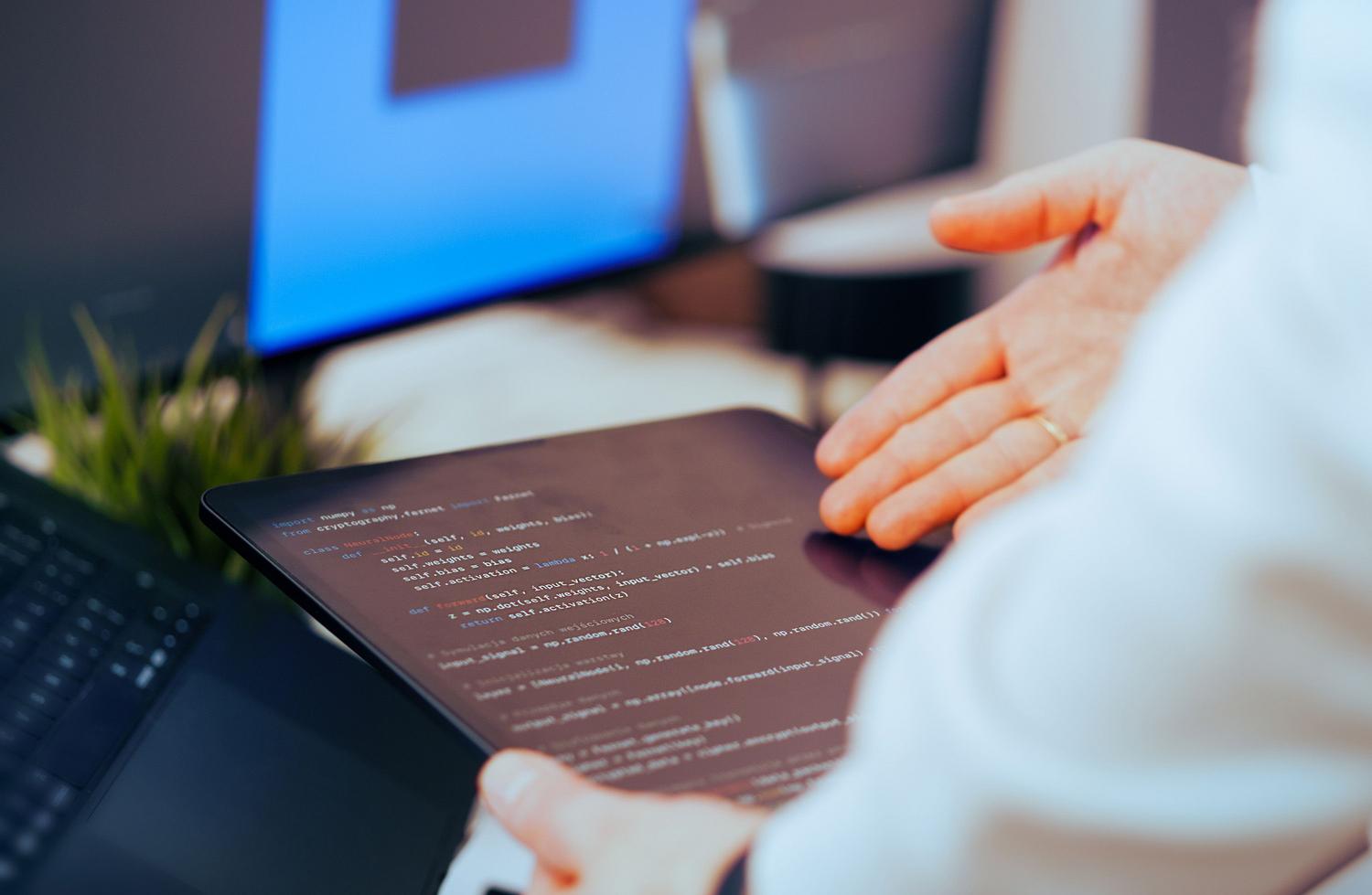 Desarrollador de software revisando código de una red neuronal en una tablet dentro de una oficina tecnológica moderna. Desarrollador de software revisando código de una red neuronal en una tablet dentro de una oficina tecnológica moderna.