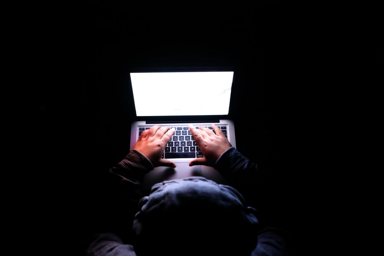 Ajustes de ChatGPT - Seguridad de la cuenta Persona utilizando un portátil en un entorno oscuro, representando la privacidad, el anonimato y la seguridad de la cuenta.