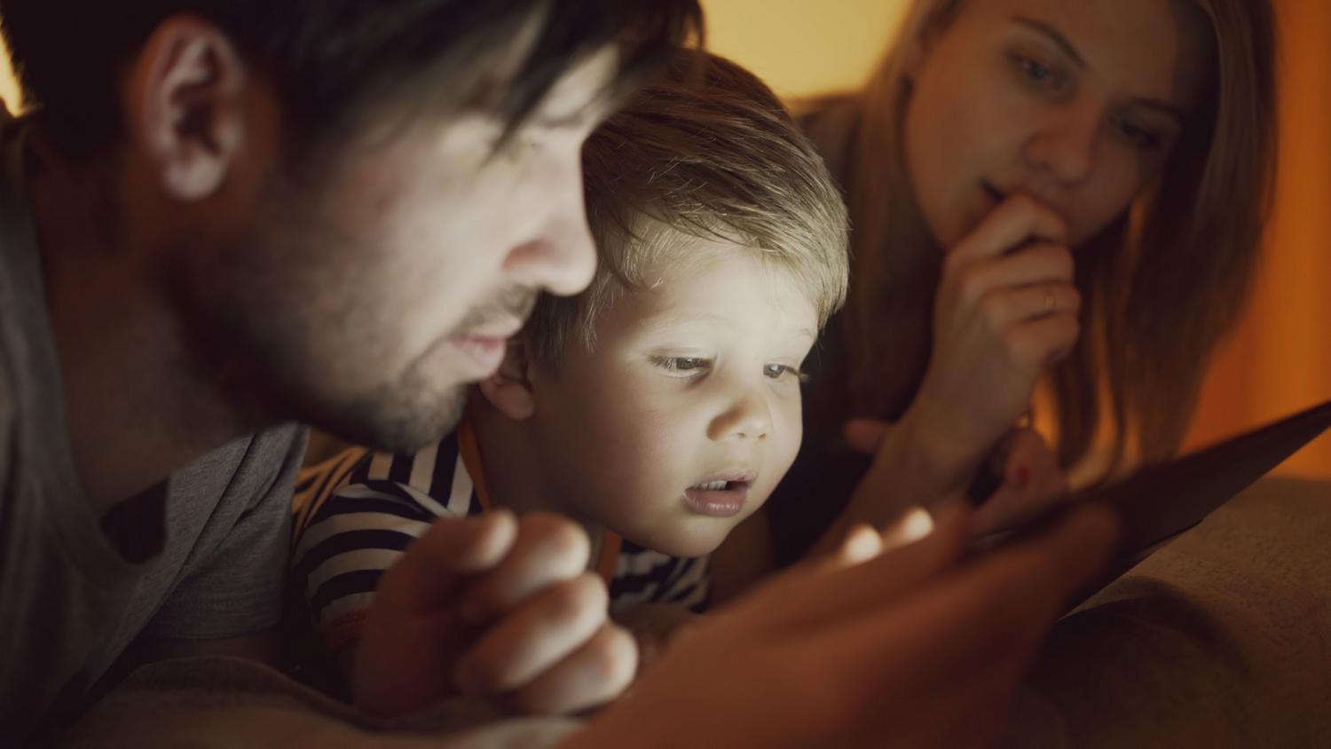 Supervisión parental Padres supervisando activamente el uso de una tablet junto a su hijo, representando el acompañamiento y la guía en el entorno digital.