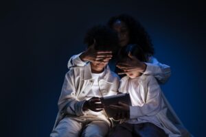Una madre cubre los ojos de sus hijos mientras usan una tablet, simbolizando la protección y el filtrado de contenidos inapropiados en internet.