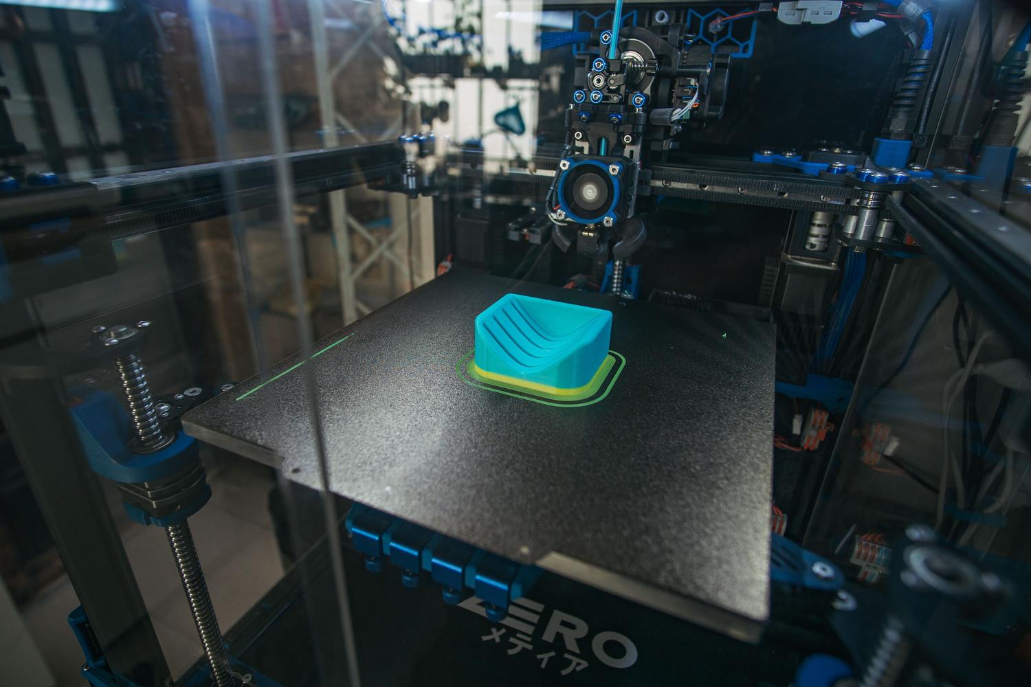 Primer plano de una impresora 3D industrial creando una pieza plástica en un entorno de producción. Primer plano de una impresora 3D industrial creando una pieza plástica en un entorno de producción.