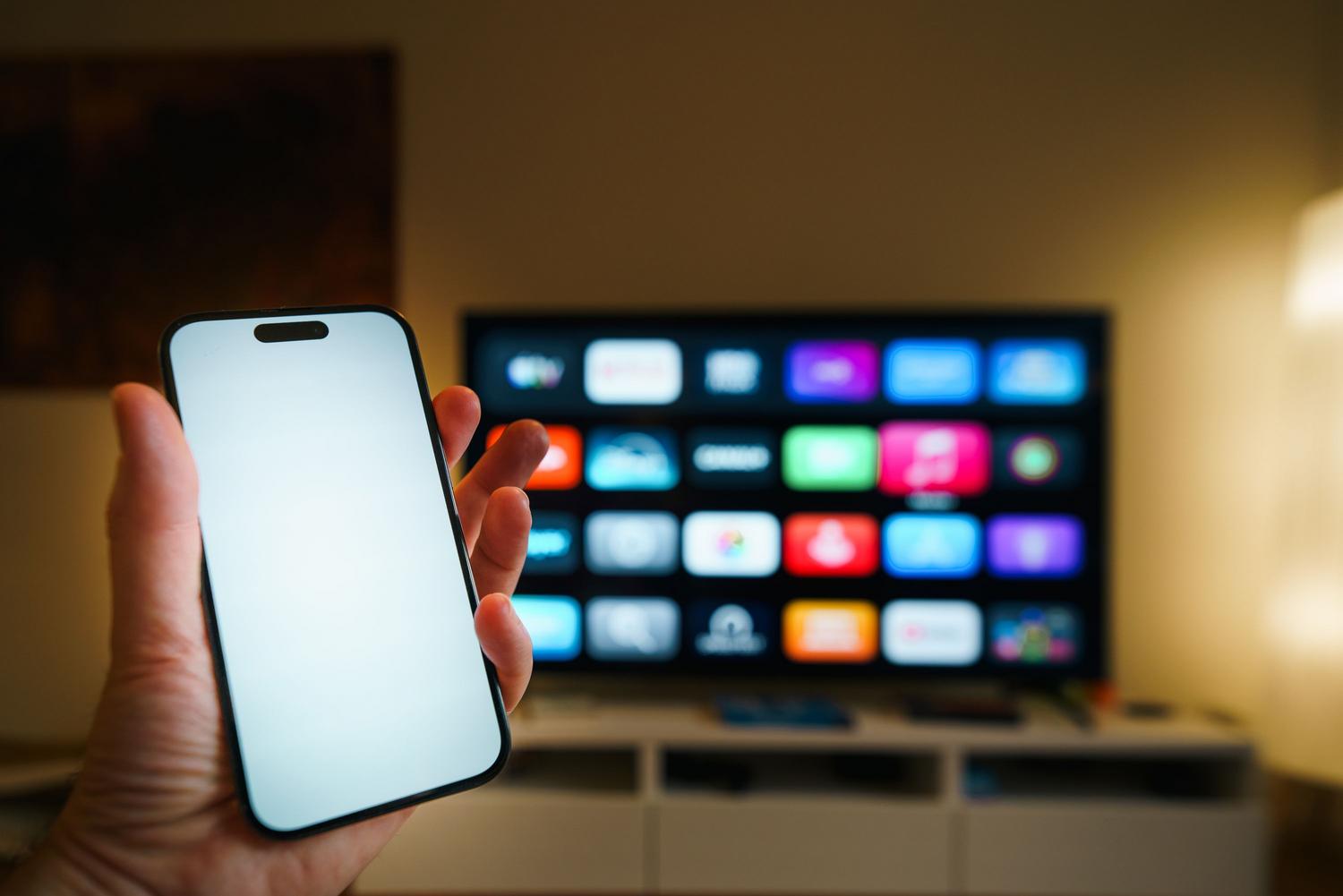 Interacción entre un smartphone y una smart TV ilustrando el ecosistema de hogar conectado e IA Interacción entre un smartphone y una smart TV ilustrando el ecosistema de hogar conectado e IA