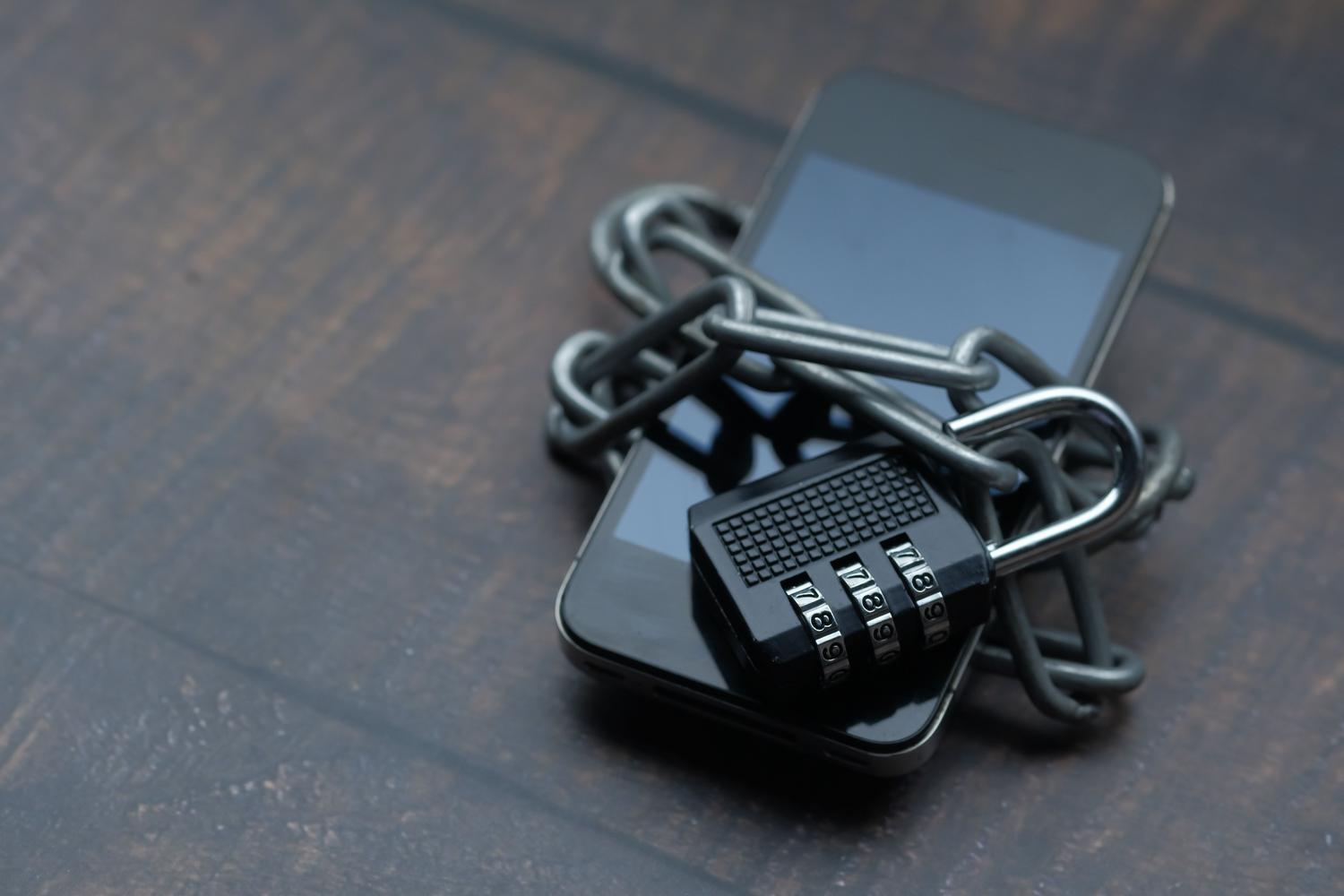 Un teléfono móvil envuelto en una cadena metálica con un candado, simbolizando la protección robusta y la verificación en dos pasos (2FA). Un teléfono móvil envuelto en una cadena metálica con un candado, simbolizando la protección robusta y la verificación en dos pasos (2FA).