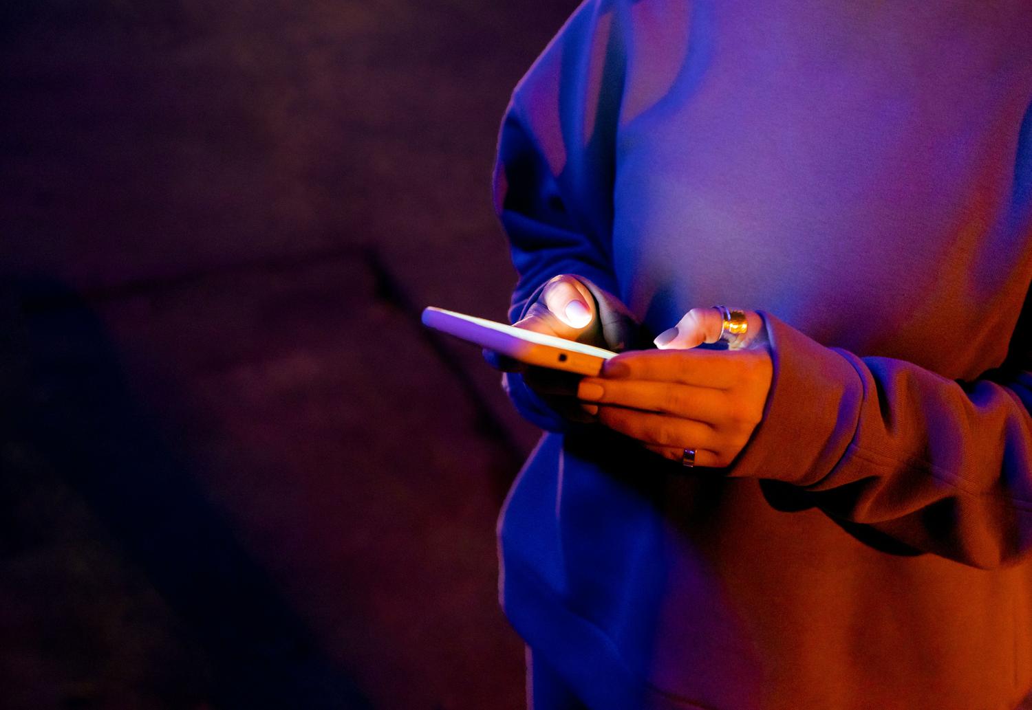 Persona utilizando un teléfono móvil en la oscuridad, resaltando el brillo de la pantalla para ilustrar la privacidad y el uso discreto. Persona utilizando un teléfono móvil en la oscuridad, resaltando el brillo de la pantalla para ilustrar la privacidad y el uso discreto.